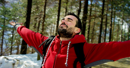 young boy dressed up in the mountains with snow and rejoices. concept of breath and clean air.