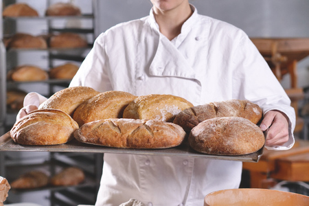 Close up of a baker showing the bread just pulled out of the oven. Concept of: artisan, baker, raw materials, love for food and traditionsの写真素材