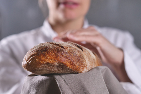 Close up of a baker showing the bread just pulled out of the oven. Concept of: artisan, baker, raw materials, love for food and traditionsの写真素材