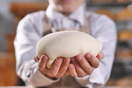 Close up of a baker little helper kneading with his hands to make bread. Concept of: artisan, baker,...