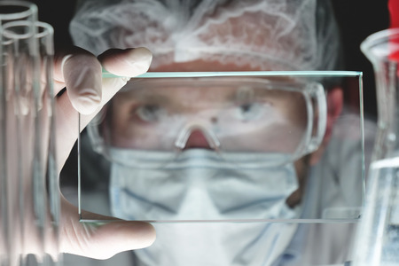 A futuristic physician, a surgeon, examines a technological digital holographic plate, a medical mask, a cap, brown eyes. Concept: futuristic medicine, new technologies, doctors, laboratory, future.の写真素材