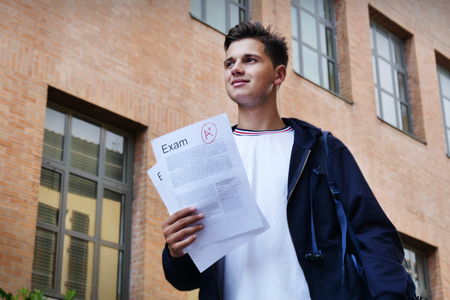 Portrait of a student showing the sheet of his exam in which he took a very high grade! Concept of: study, educational, school and university, and happiness.の写真素材