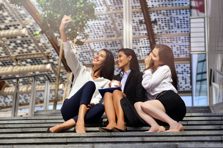 Business women of different ethnic backgrounds dressed in suits and suits, they take a picture in which they smile and they are all happy. Concept of: internationality and technology, social networksの写真素材
