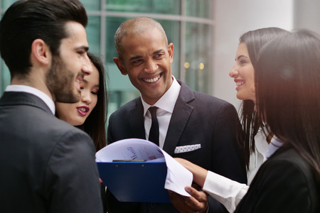 Business people from different ethnic groups dressed in suits and ties, talk about the performance of the financial markets and the world economy. Concept of: internationality and career, cooperationの写真素材