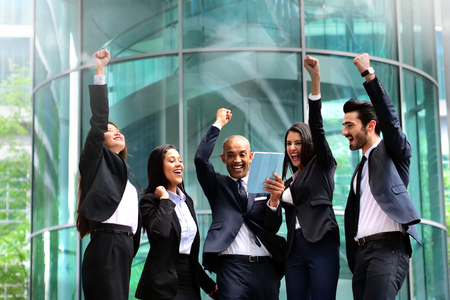 A group of business people from different backgrounds to rejoices and celebrates their success in financial and economic fields. Concept of: team work, internationality and success.の写真素材
