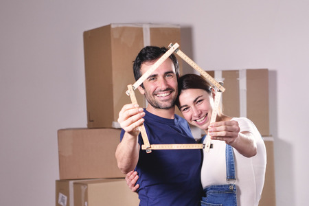 Just love a house and is moving. The bride and groom smile and hold the house. Concept of: future, family, mortgage and loan.の写真素材