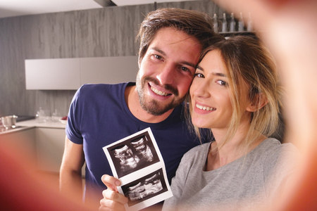 A couple in love videocall their parents using a tablet, to announce the birth of their son showing...