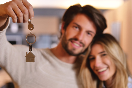 They are just a house and they are moving. The bride and groom smile and hold the keys to the new house. Concept of: future, family.の写真素材