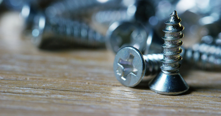 bolts and screws on a wooden work bench. concept of new screws or bolts. working tools in carpentry and home. and self-tapping steel screwsの写真素材