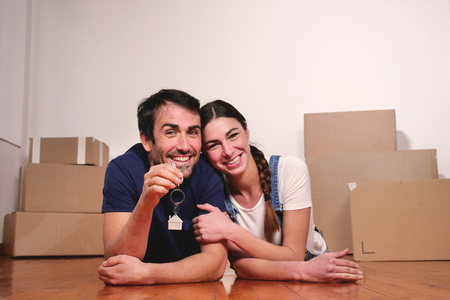 They are just a house and they are moving. The bride and groom smile and hold the keys to the new...
