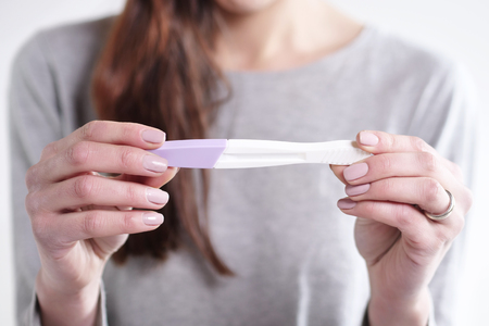 A beautiful woman takes a pregnancy test and she will be pregnant, she will explode in the future of her child. Concept of: birth, life, familyの写真素材