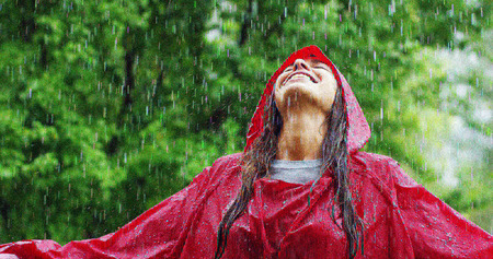 girl smiles, spins and laughs in the rain. the rain falls, the drops fall on his face and the girl is happy with life and nature around. concept of nature and happy life. Adventure, purity.の写真素材