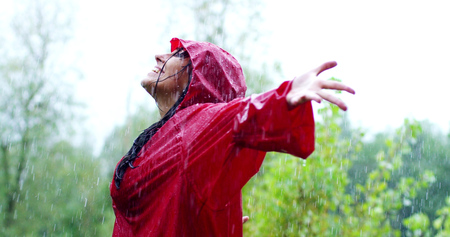 girl smiles, spins and laughs in the rain. the rain falls, the drops fall on his face and the girl is happy with life and nature around. concept of nature and happy life. Adventure, purity.の写真素材