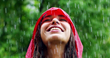 girl smiles, spins and laughs in the rain. the rain falls, the drops fall on his face and the girl is happy with life and nature around. concept of nature and happy life. Adventure, purity.の写真素材