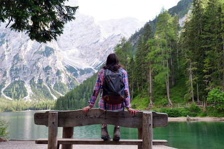 A beautiful woman makes trekking it rests on a wooden bench. The woman is happy and enthusiastic about her. Concept of: freedom, exploration, breatheの写真素材