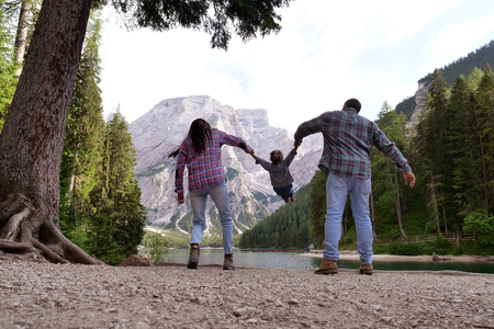 Plays a family on a holiday in the mountains. Mom and dad swing their daughter. Concept of: love, family, holidays, freedom.の写真素材