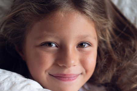 Smiling girl looking at camera. Concept of: relaxation, peaceful dreams, waking up in the morning.の写真素材