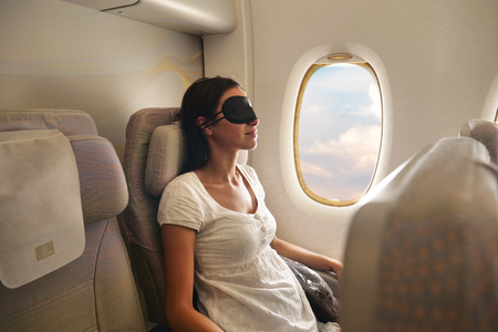 A woman relaxes on the plane while looking at the clouds. Concept of: travel, vacation and transport.の写真素材