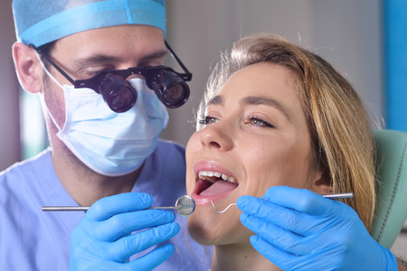In a professional practice, a dentist checks the dentition of the patient, and shows the perfect white teeth. Concept of: dentists, healthcare, perfect smile.の写真素材