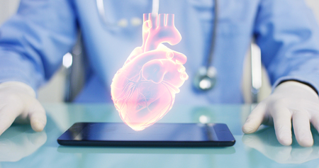 A physician, surgeon, examines a technological digital holographic plate representing the patient's body, the heart lungs, muscles, bones.の写真素材