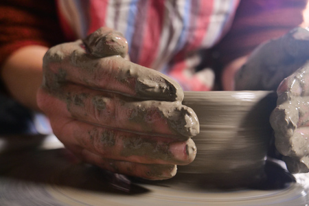 An expert potter, he creates with clay and his hands in a beautiful vase in his laboratory. The artisan creates works of art with his hands. Concept of: experience, art, tradition, clay.の写真素材