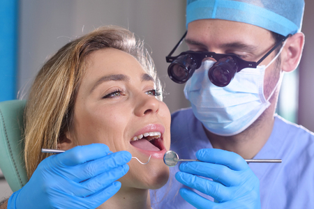 In a professional practice, a dentist checks the dentition of the patient, and shows the perfect white teeth. Concept of: dentists, healthcare, perfect smile.の写真素材