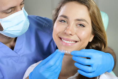 In a professional practice, a dentist puts the latest generation of transparent dental appliances into order. Concept of: dentists, healthcare, perfection, white.の写真素材