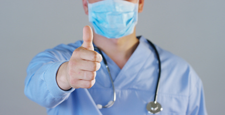 A doctor or surgeon in a medical mask, a respirator, brown eyes, goggles, a surgical cap, a hospital or clinic.の写真素材