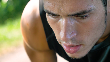 Portrait of a handsome young guy in sportsman, holding a phone, smiling, wearing sports clothes, running outside. Concept: love sports, healthy lifestyle, beautiful, muscles, happy, burn calories.の写真素材