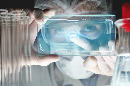 A futuristic physician, a surgeon, examines a technological digital holographic plate, a medical mask, a cap, brown eyes. Concept: futuristic medicine, new technologies, doctors, laboratory, future.の写真素材