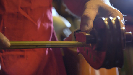 The professional violin master makes a violin with his own hands, spruce, pine, glasses, planes, tunes strings. Concept: spiritual instrument, made hands, art, music, melody, soundの写真素材