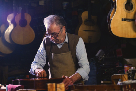 In his laboratory, a liutist builds high quality guitars for musicians, working fine wood. Concept...
