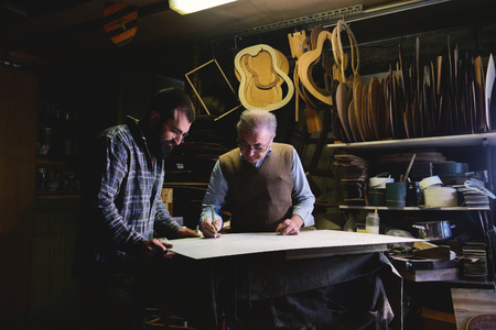 n laboratory, two liutist builds high quality guitars for musicians, working fine wood. Concept of: music, tradition, ancient crafts.の写真素材