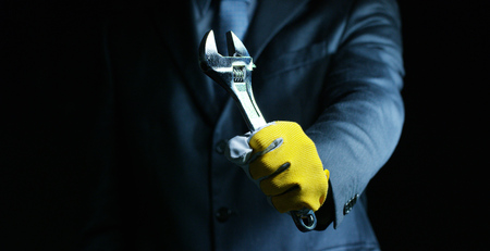 A man dressed in a suit and tie, showing a wrench mechanic. Concept: car insurance, mechanical, leasingの写真素材