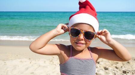 A little girl is in a bathing suit, wearing sunglasses, on a background of blue sky.の写真素材