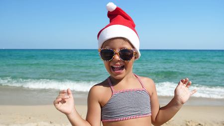 A little girl is in a bathing suit, wearing sunglasses, on a background of blue sky.の写真素材