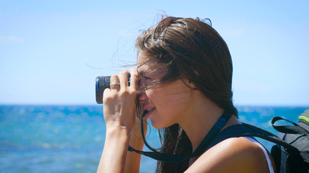 A female tourist photographer with a beautiful view of the blue sea and sky. Concept: travel,...