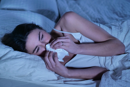 A woman in bed feels sick and has symptoms of colds, fever and stomach ache. Concept of: vaccines, disease, medicines.の写真素材