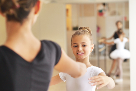 A teacher of classical dance teaches some steps to a young student who wants to learn how to dance. Concept of: ambition, education, teaching and love for the danceの写真素材