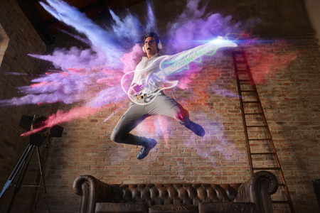 man jumps with colorful background playing a virtual guitar. concept of freedom and creativity with...