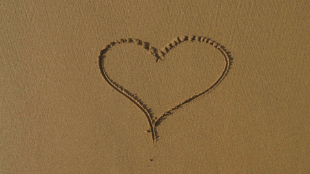 Beautiful painted heart on brown sand, sunset, sea background. Concept: rest, love, style life, sea,...