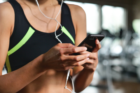 A beautiful young woman smiles while listening to music at the gym.