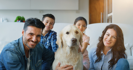 Portrait of a happy family in a living room. Concept of happy family, love for animals, childhoodの写真素材