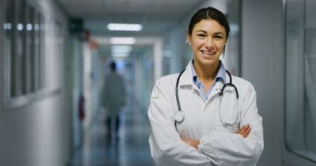 Portrait of a smiling female doctor with a job in a corridor of a hospital. Concept of medicine, technology, health care and people, hospitalの写真素材