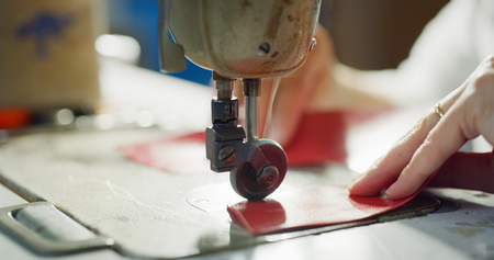 Close up of a shoemaker sewing with red leather Concept: handmade, fashion, industrial, factory.の写真素材