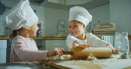 Two little girls in the kitchen prepare food, a dessert for the family. They start to cook and start...