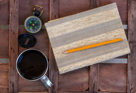 compass and notepad with pen on brown wood table background