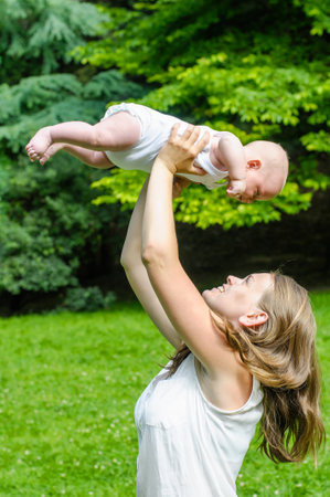 mother throwing up newborn baby in summer parkの写真素材