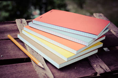 multicolored notepads with pen on brown wood table background