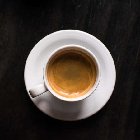 coffee cup on black wooden table in cafeの写真素材
